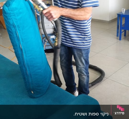 אדם מנקה ספה עם מכשיר שאיבה